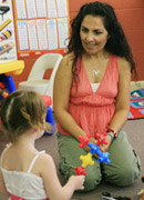 Picture of child care worker kneeling down to talk with a child.