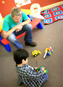 childcare worker watching a child playing alone.