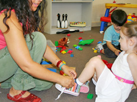 childcare worker tying their own shoelace while the child watches