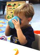 a boy drinking from a plastic mug.