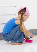 a child sweeping with a child-sized brush and pan.