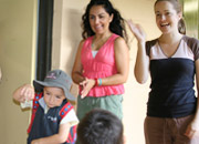 Picture of a childcare worker farewelling a family member and child as they leave the centre. 'See you next time?'