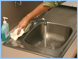 person turning off the tap with a paper towel.