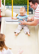 a person helping a young child down the slide.