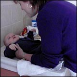 Woman talking to the baby while placing it on the change table