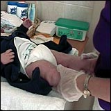 Woman wearing gloves while taking the nappy off the baby