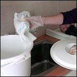 Woman placing soiled nappy in a nappy bucket