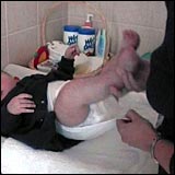 Woman lifting up the baby's legs and placing a clean nappy on his bottom