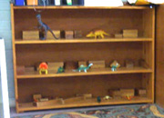 a shelf containing wooden blocks and dinosaur toys.